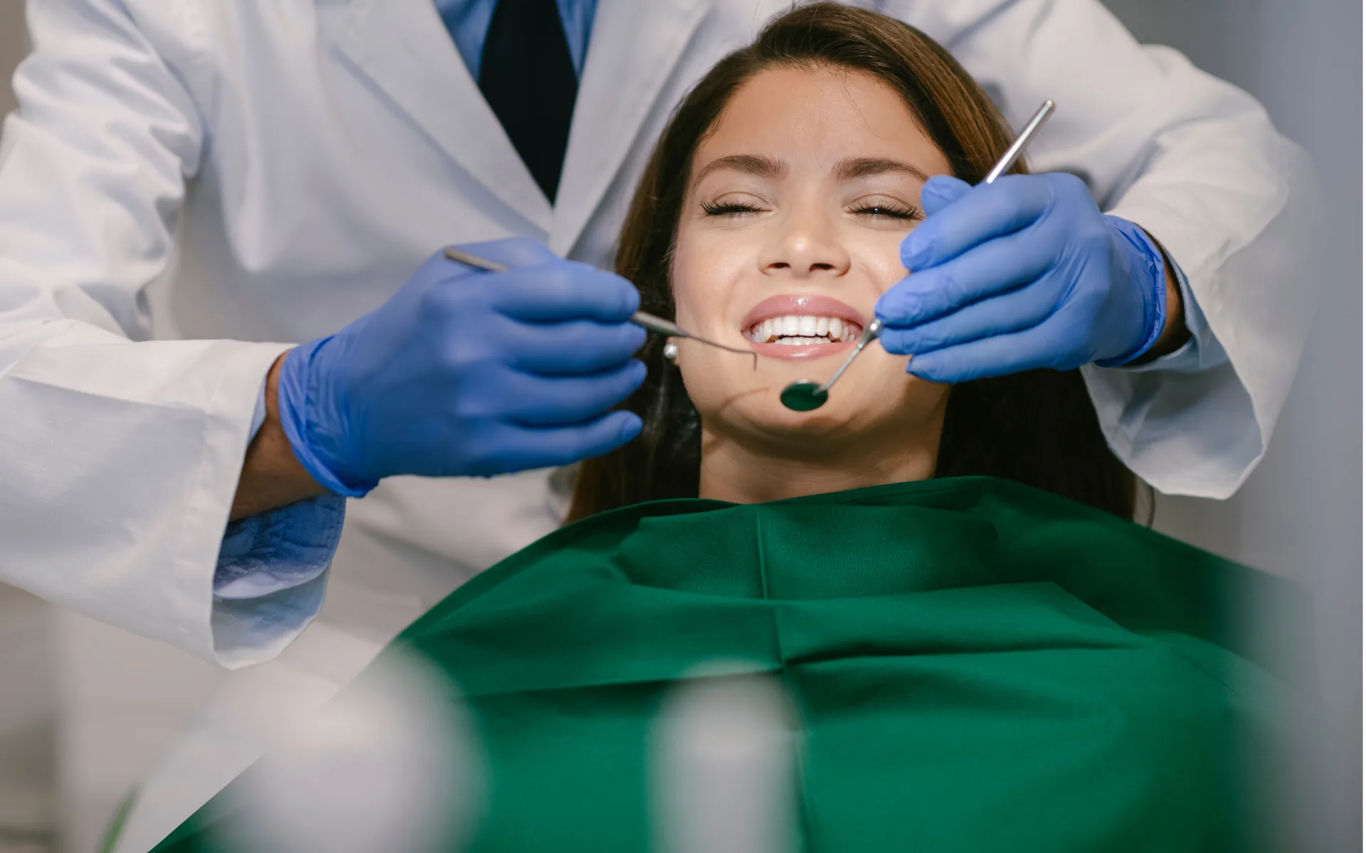 Examen dentaire de contrôle : le médecin-dentiste inspecte les dents d’une patiente au miroir