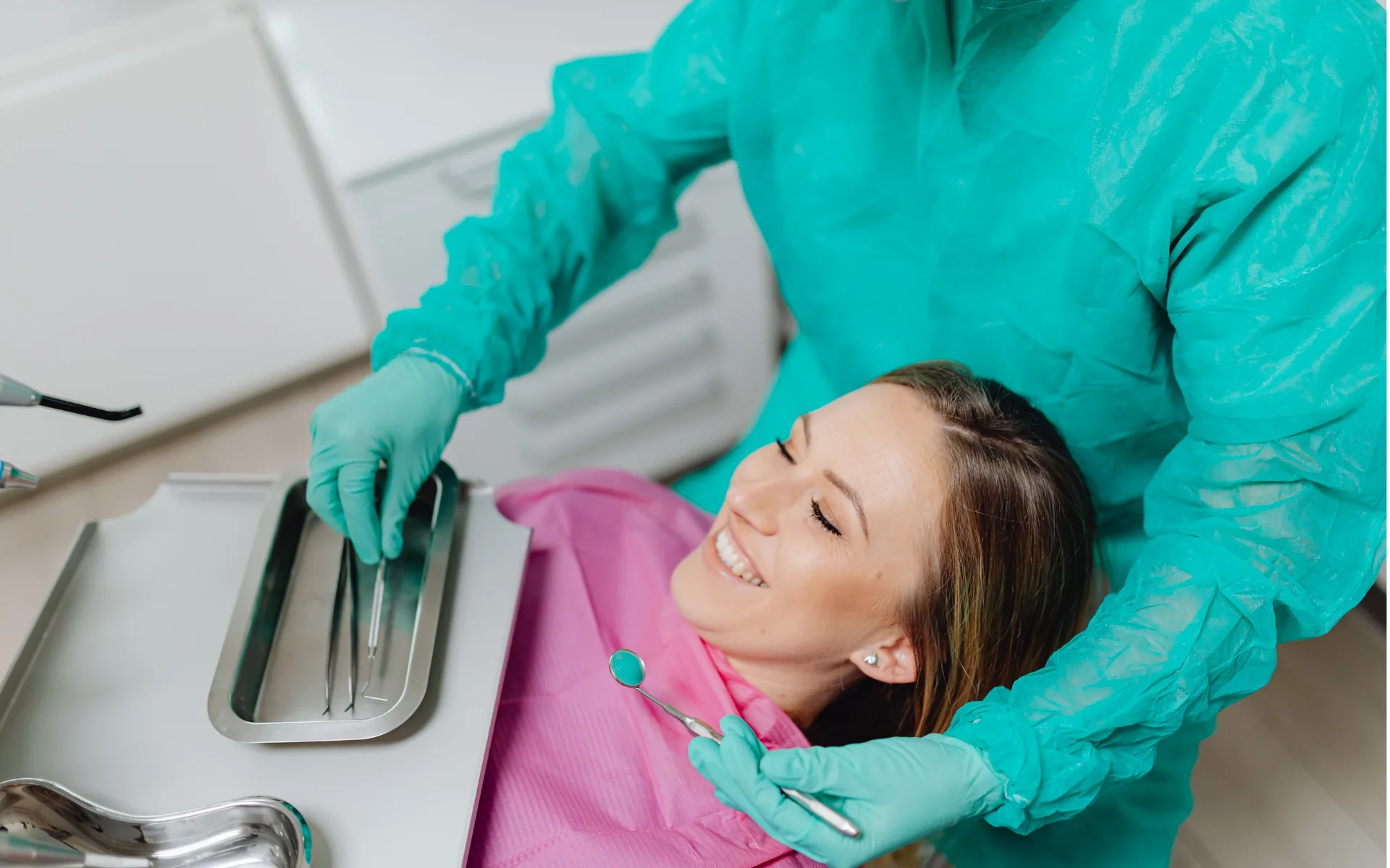 Le médecin-dentiste prépare ses instruments, la patiente installée au fauteuil de soin