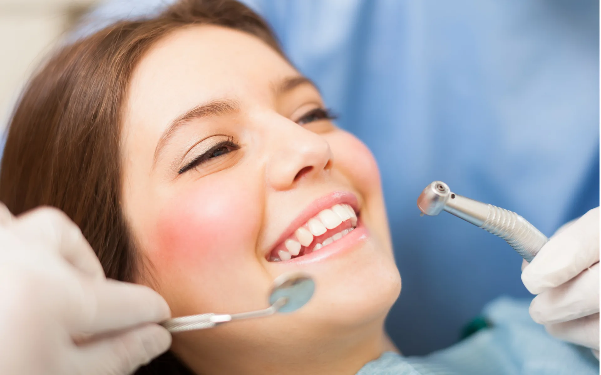 Séance de détartrage, l’instrument approché des dents d’une patiente installée au fauteuil