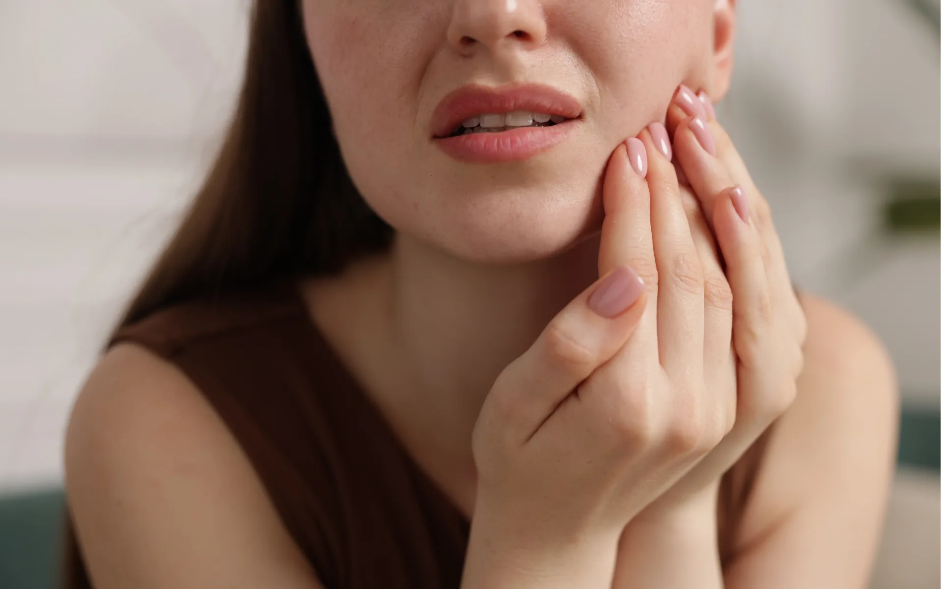 Patiente portant la main à sa joue, gênée par une douleur dentaire