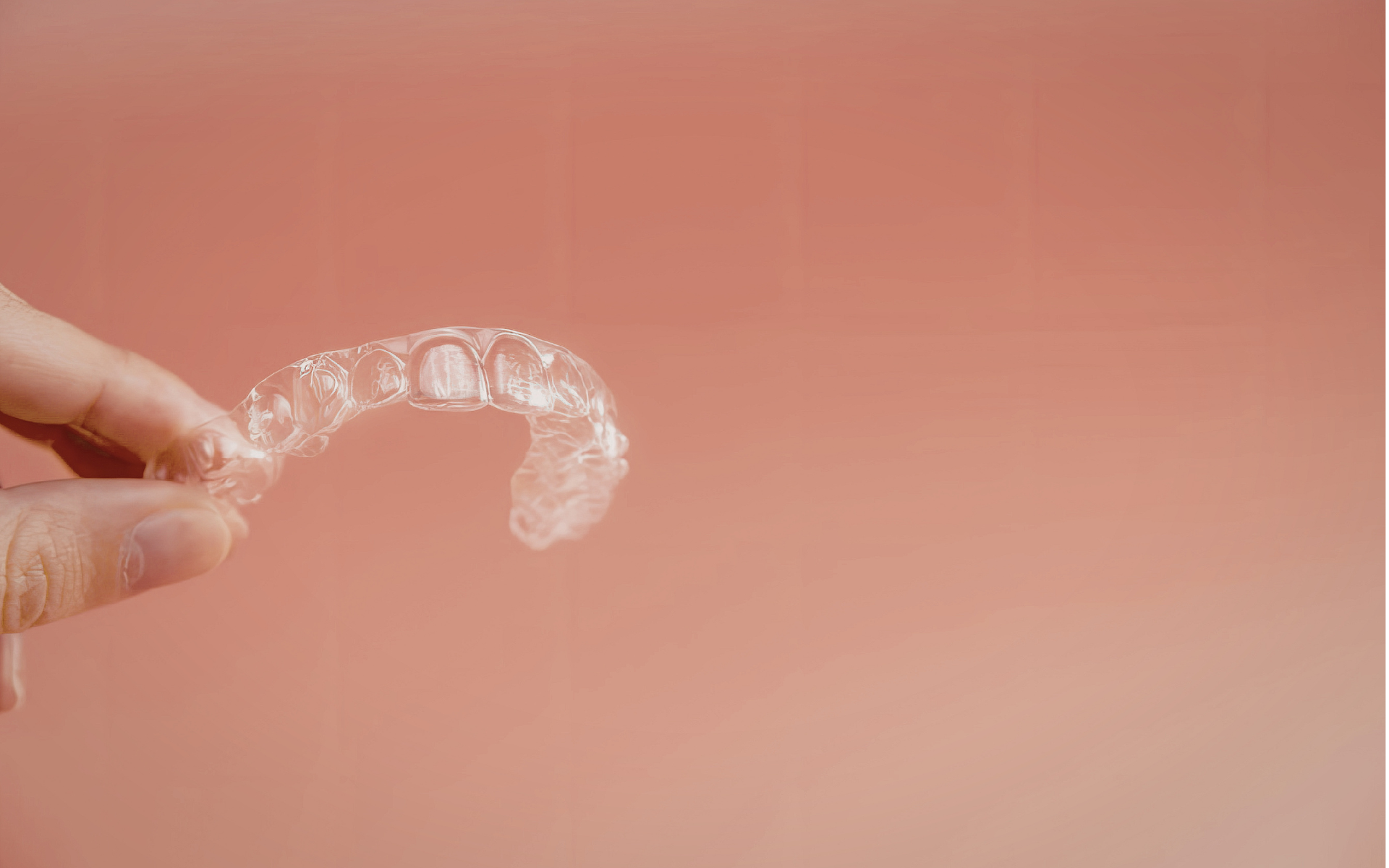 Une main présente une gouttière transparente d’orthodontie